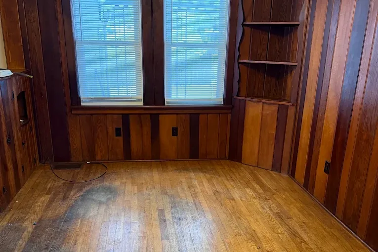 The same living room, emptied down to bare hardwood floor.